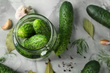 Glass jar with cucumbers prepared for pickling, on grey background