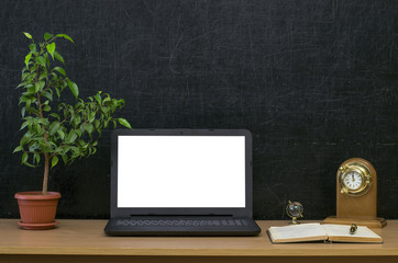 Teacher or student desk table. Education background. Education mockup concept. Laptop with blank screen, open copybook, clock watch, globe and plant in the pot on blackboard (chalkboard) background.