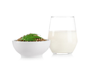 Glass of hemp milk and bowl with seeds isolated on white