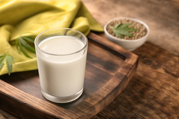 Glass of hemp milk on wooden board
