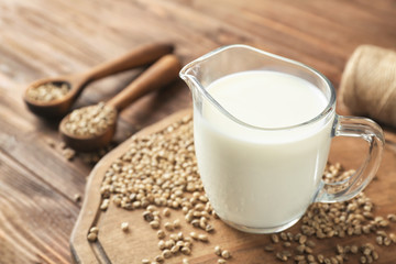 Jug with healthy hemp milk on wooden board