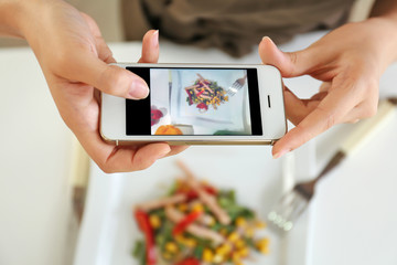 Female blogger making photo of freshly cooked salad in kitchen
