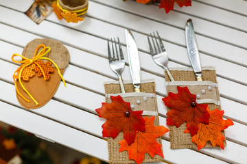 Dining utensils forks and knifes serving a wooden table decorated with autumn leaves, rowan berries, chestnuts, walnuts on a wooden background in rustic style