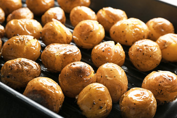 Many baked potatoes on grill pan, closeup