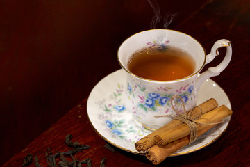 Bone china teacup with cinnamon on a dark wooden background