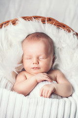 Sleeping newborn baby in a wrap on white blanket.