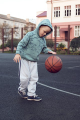 little boy kid playing basketball at streetball court