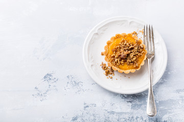 Thanksgiving day concept with homemad pumpkin tartlet, mini pie, on gray stone background. Healthy autumn food, copy space.