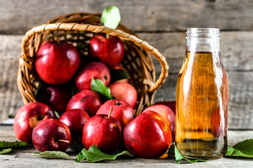 Organic apple juice in a bottle and red apples on rustic table, healthy dieting and wellbeing concept