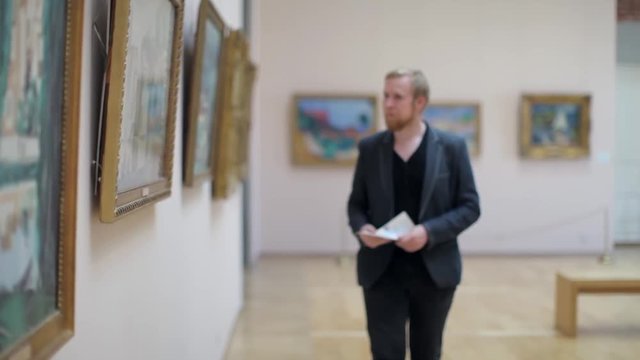Man in a Suit Looks at a Picture in a Museum