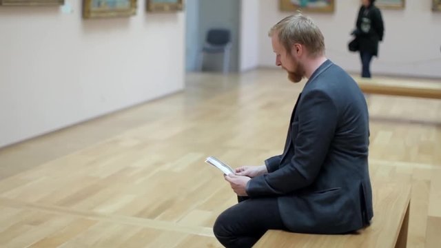 Man With a Booklet, Map Sits in the Picture Gallery