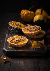 Thanksgiving day concept with homemad pumpkin tartlet, mini pie, on wooden background. Healthy autumn food.