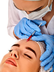 Fototapeta premium Filler injection for female forehead face. Plastic aesthetic facial surgery by doctor in beauty clinic. Facing skin with Botox. Doctor in medical gloves with syringe. Wrinkle removal.