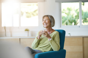 Senior woman relaxing in armchair drinking hot tea