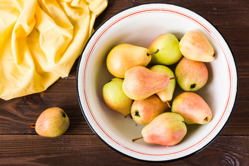 Ripe pears in an enamel plate on a wooden table. Top view