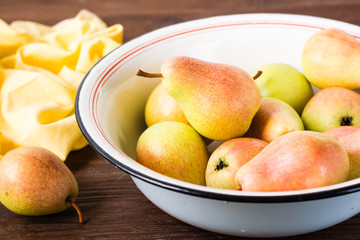 Ripe pears in an enamel plate on a wooden table