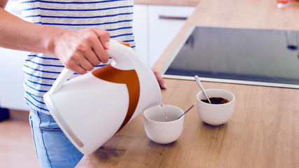 Unrecognizable woman preparing turkish coffee. Pouring water into a cup.
