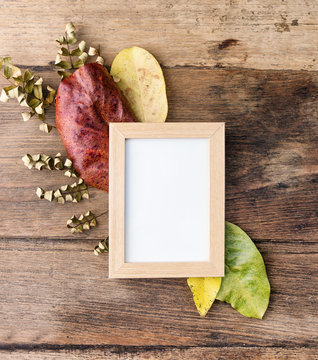 Flat lay photo frame with autumn leaves on old table. Rustic mock up, background