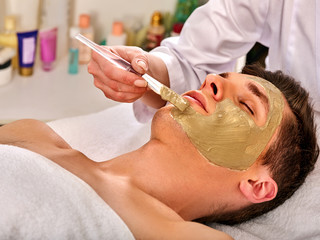 Obraz na płótnie Canvas Mud facial mask of woman in spa salon. Massage with clay full face. Girl on with therapy room. Removing black dots. Beautician with bowl therapeutic procedure isolated background.