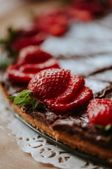 Sliced strawberry and chocolate pie on a wood board from the candy bar table.