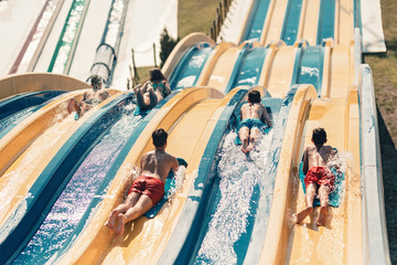 Young people having fun on the water slide with friends and familiy in the aqua fun park glides,...