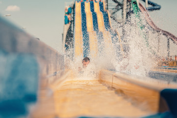 Young people having fun on the water slide with friends and familiy in the aqua fun park glides,...