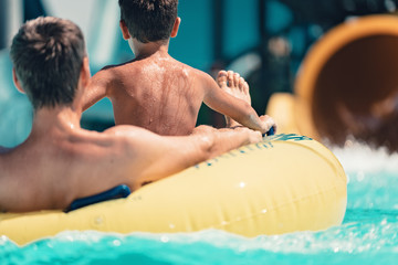 Young people having fun on the water slide with friends and familiy in the aqua fun park glides,...