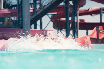 Young people having fun on the water slide with friends and familiy in the aqua fun park glides,...