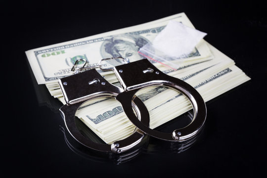Handcuffs on stack of dollar banknotes and cocaine