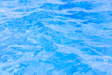 Close-up of crystal-clear water with sunshine in the swimming pool, background, texture. Swimming conception. Shallow depth on focus.
