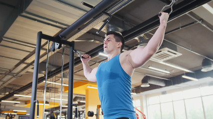Bodybuilder training in the gym - young muscular man perform training for biceps, slider shot