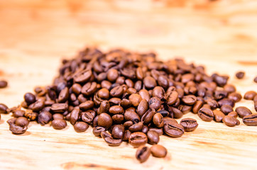 Pile of the roasted coffee beans on wooden table