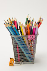 A group of colored pencils in a writing-glass on a white background