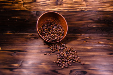 Roasted coffee beans in bowl on wooden table