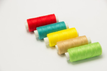 Coils with threads of different colors and synthetic flowers on a white background