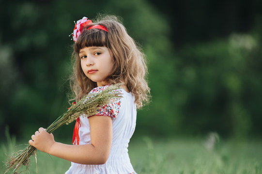 Little beautiful girl walks in the forest and collects field plants. Spring.