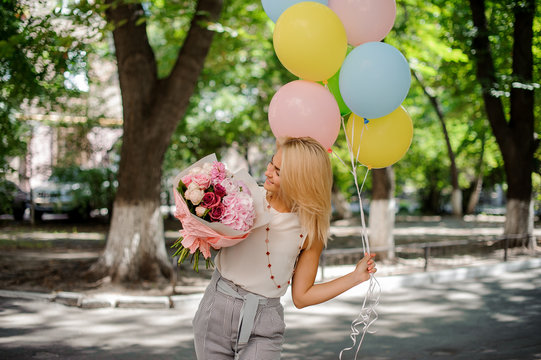 Birthday girl holding a bouquet of flowers and balloons
