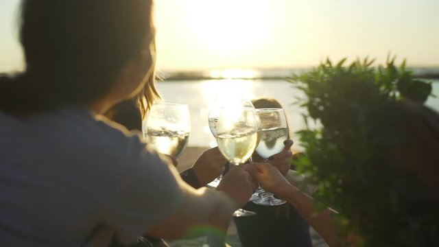 Girls clink wine glasses seaside sunrise close up rapid slow motion