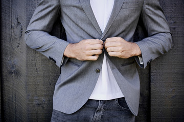 Guy in jeans buttoning suit jacket, close up