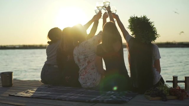 Five silhouette girls clink wine glasses seaside sunrise rapid slow motion