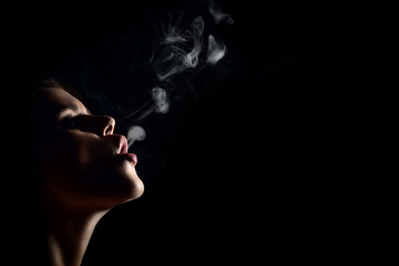 Fototapeta premium beautiful young woman smoking on black background with copy space