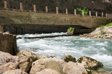 Obraz premium a mountain river runs under an old bridge in the mountains, rocks