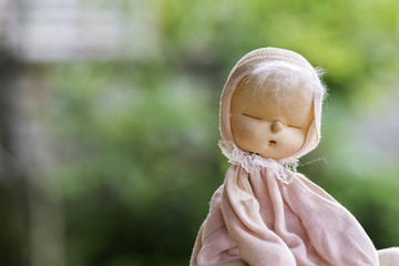 Baby girl doll in pink pajamas sitting on wooden floor.