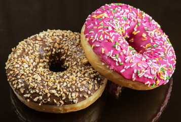 assorted doughnuts in the glaze and colorful sprinkles on a black background