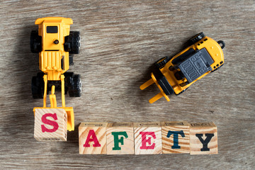 Toy plastic bulldozer hold toy block letter s to fulfill word safety with forklift on wood...