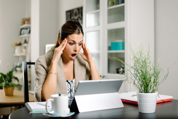 Obraz premium Casual worried woman working from home and suffering job issues. Female entrepreneur in trouble.