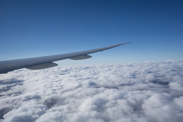Fototapeta premium Airplane wing above cloud under clear blue sky.