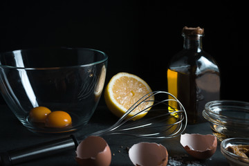 Yolks in a bowl, whisk for whipping, mustard and olive oil side view