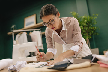 Female tailor designing clothes pattern on paper