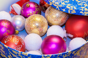 Christmas toys colored balls are lying in blue round box with open cover.